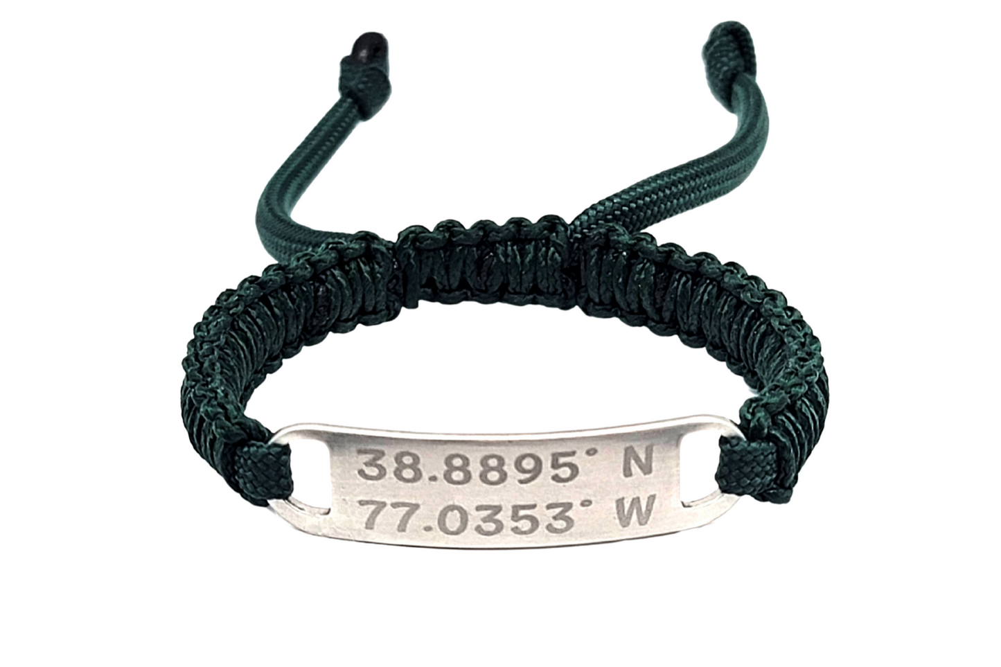 A dark green adjustable micro paracord bracelet with a stainless steel tag engraved with coordinates. The bracelet is displayed on a white background.