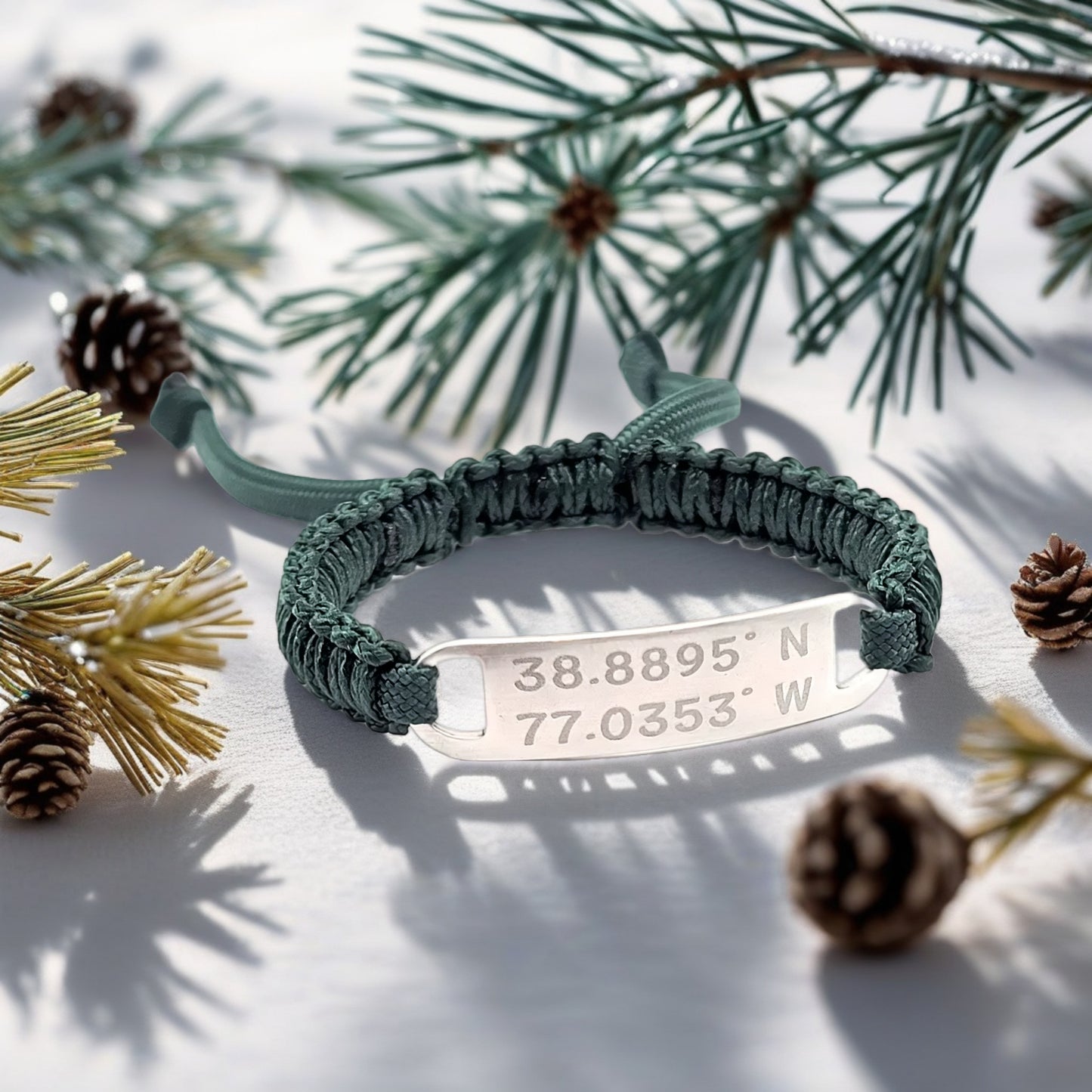 Dark green bracelet on a white table with snowy pine branches, showcasing the engraved tag in a festive setting