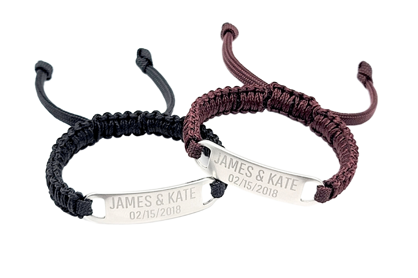 Close-up of two matching adjustable micro paracord bracelets, one maroon and one black, with engraved text James & Kate 02/15/2018 on the metal plates. The bracelets are arranged in a slightly overlapping position on a clean white surface.