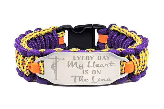 Colorful thin 275 paracord ID bracelet with a silver, stainless steel ID tag engraved with Every Day My Heart is on the Line and a lineman symbol, displayed on a white background.