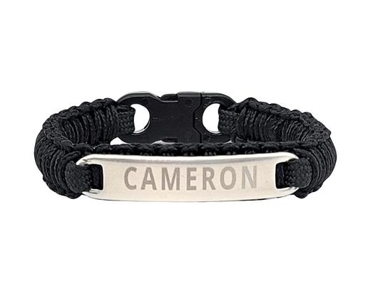 Front view of a black micro paracord bracelet featuring a stainless steel tag engraved with the name Cameron, showcasing a sleek and durable design with a black plastic buckle, displayed on a plain white background.