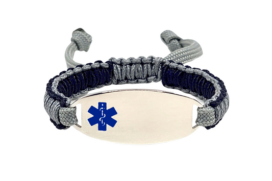 An adjustable micro paracord bracelet displayed on a clean white background. The bracelet features a polished silver oval tag engraved with a blue medical alert symbol, and the paracord is woven in navy blue and light gray colors.