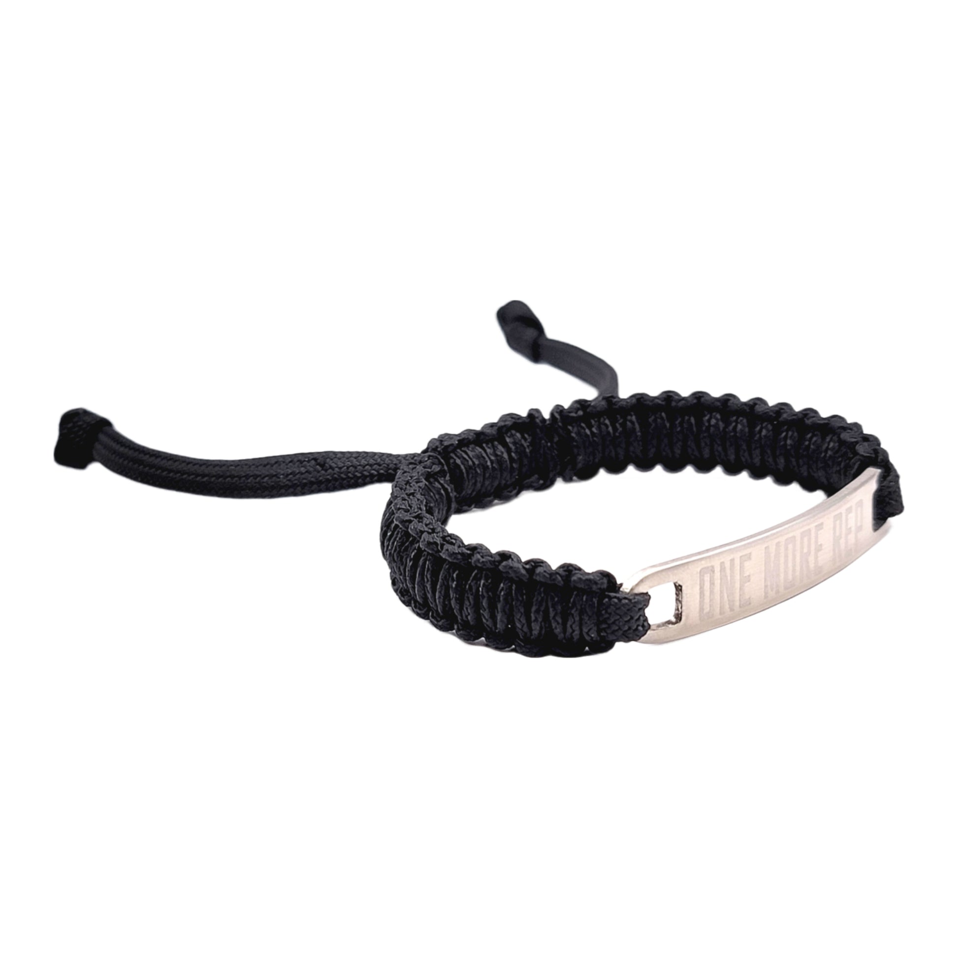 A side view of a black micro cord bracelet with "One More Rep" engraved on a metal tag, showcasing the adjustable cord design, displayed on a white background.