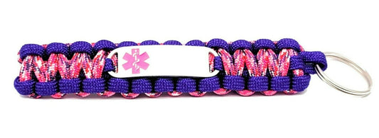 Brightly colored purple and pink paracord medical ID keychain with a silver, stainless steel ID tag with a pink enameled medical symbol, displayed on a white background.