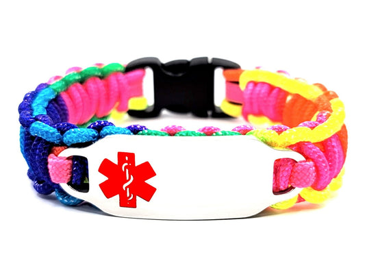 Rainbow colored, thin, 275 paracord medical alert bracelet with a silver colored, stainless steel ID tag with an enameled red medical symbol, displayed on a white background.