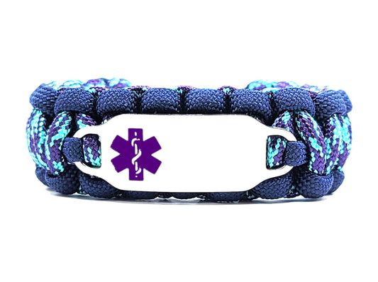 Navy blue, purple and turquoise paracord medical alert bracelet with a silver colored, stainless steel ID tag with an enameled purple medical symbol, displayed on a white background.