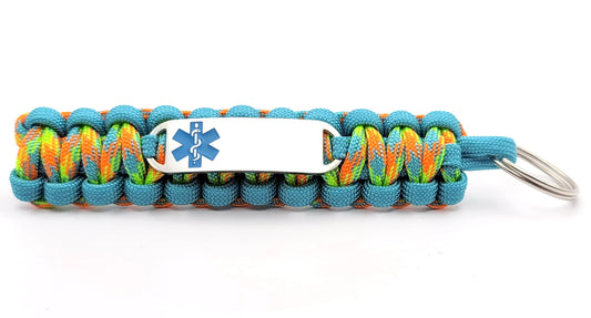 Brightly colored light blue and multicolored paracord medical ID keychain with a silver, stainless steel ID tag with an ocean blue enameled medical symbol, displayed on a white background.